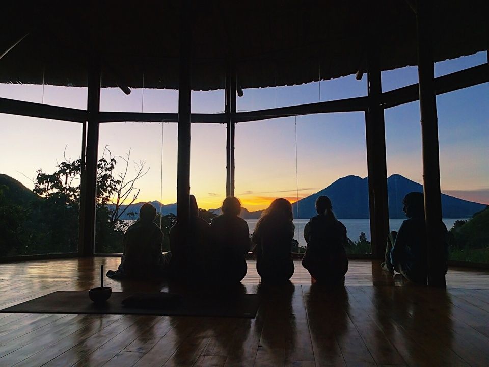 A class seated together in a shala, facing the lake.