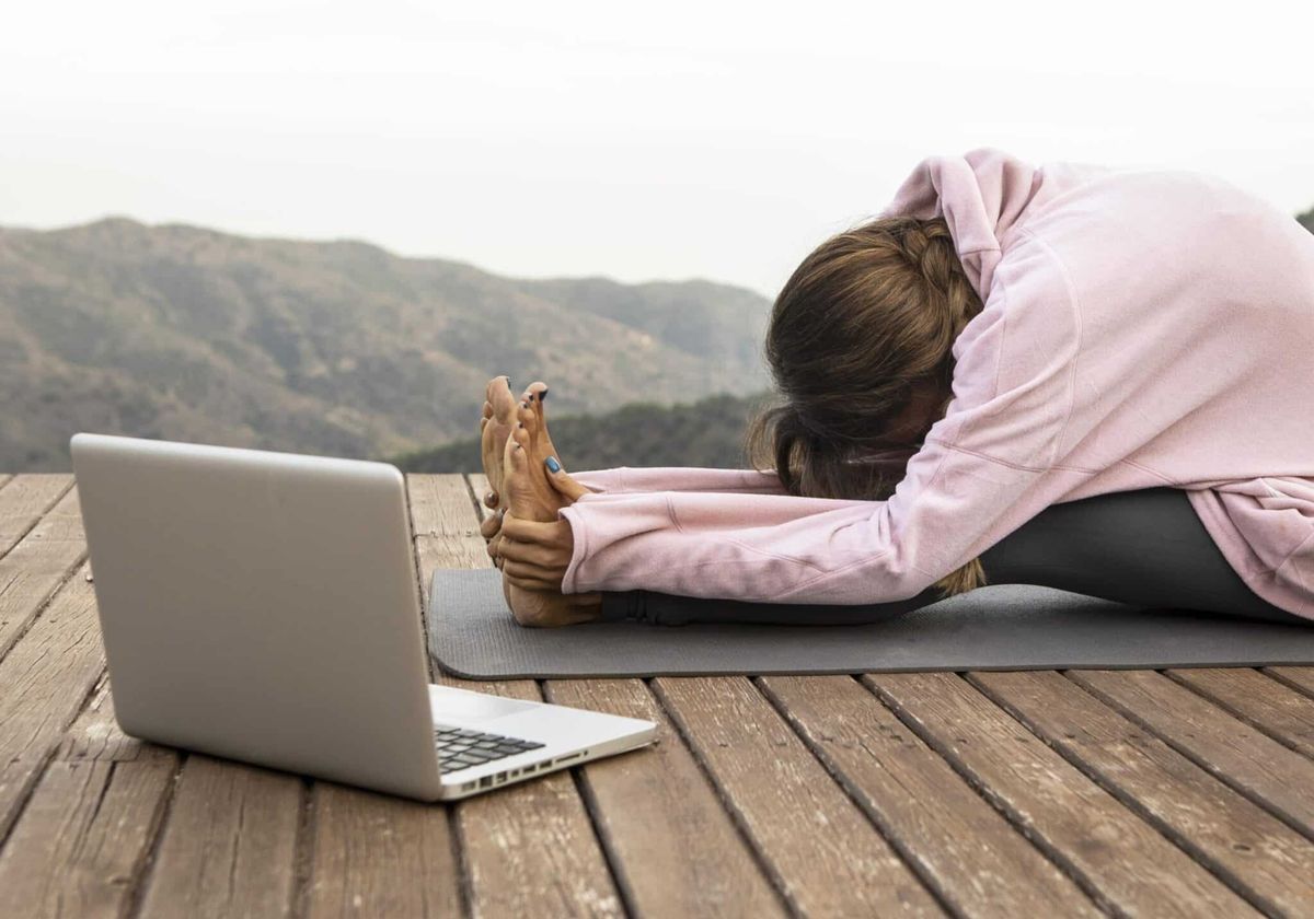 Child's pose beside an open laptop.