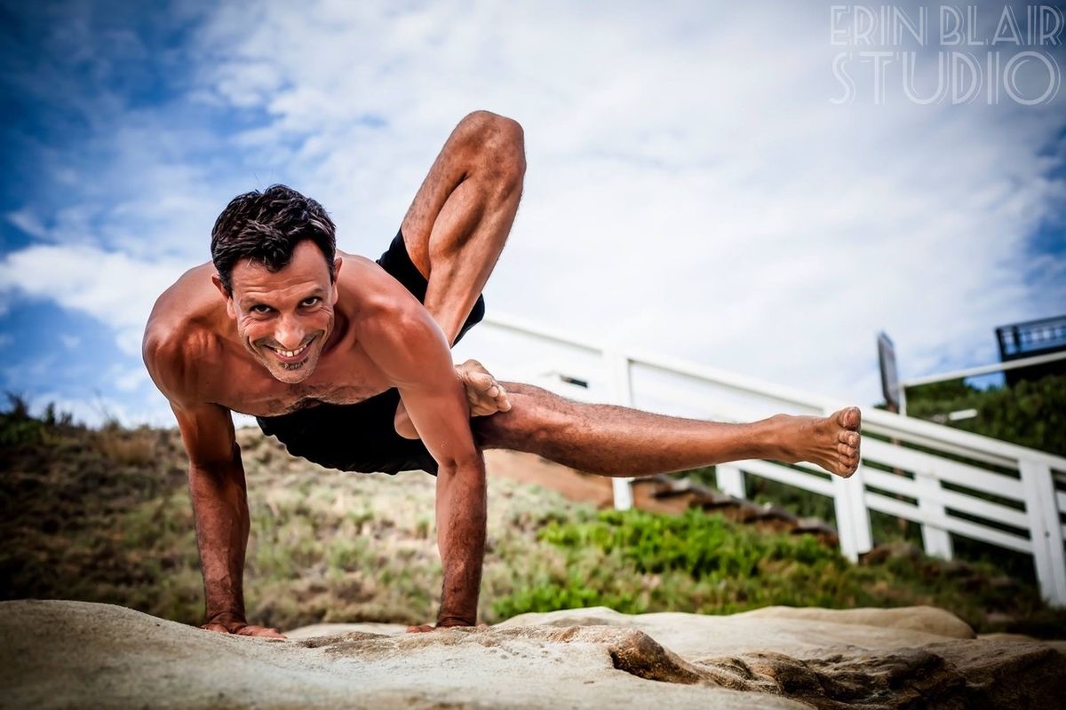 An arm balance with one leg extended.