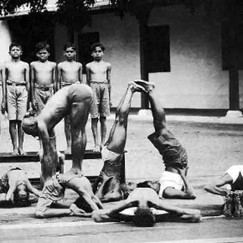 A historical photograph of a yoga practice, with headstands and seated poses.