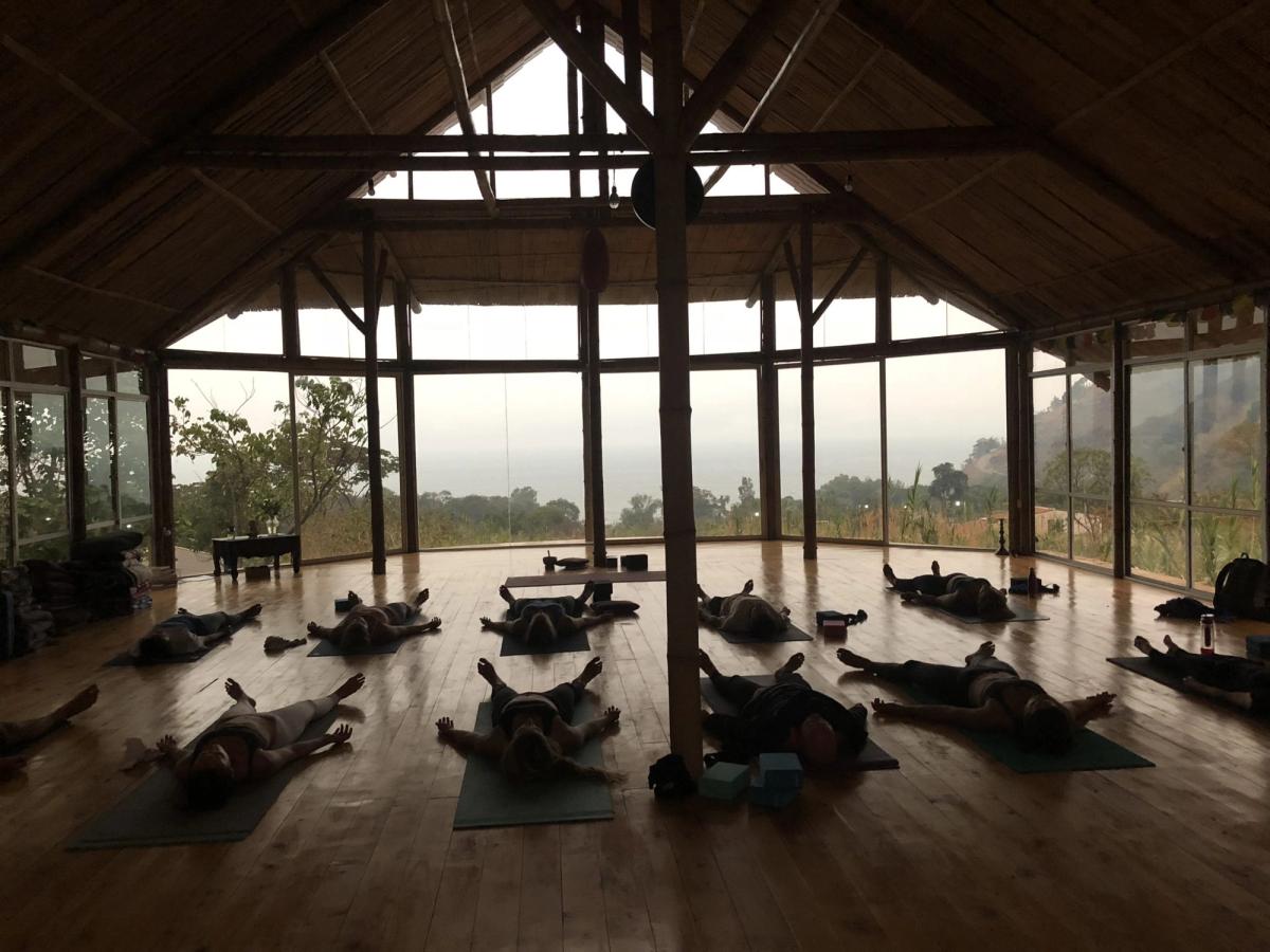 A class resting in savasana in a wooden shala.