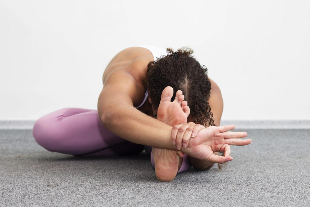 A seated forward fold, hands holding the feet.