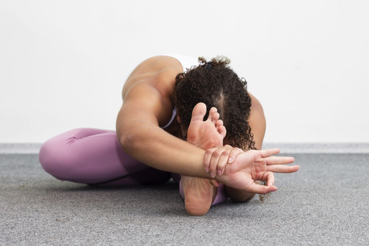 A seated forward fold, hands holding the feet.