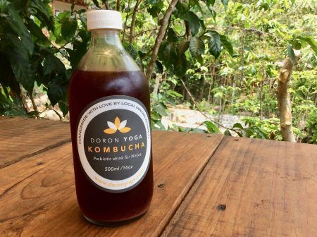 A bottle labeled Doron Yoga kombucha on a wooden table.