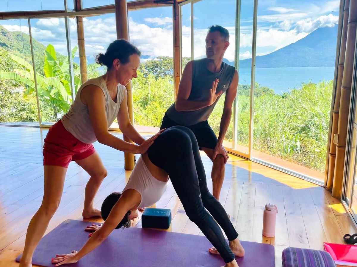 A teacher assisting a standing forward fold.