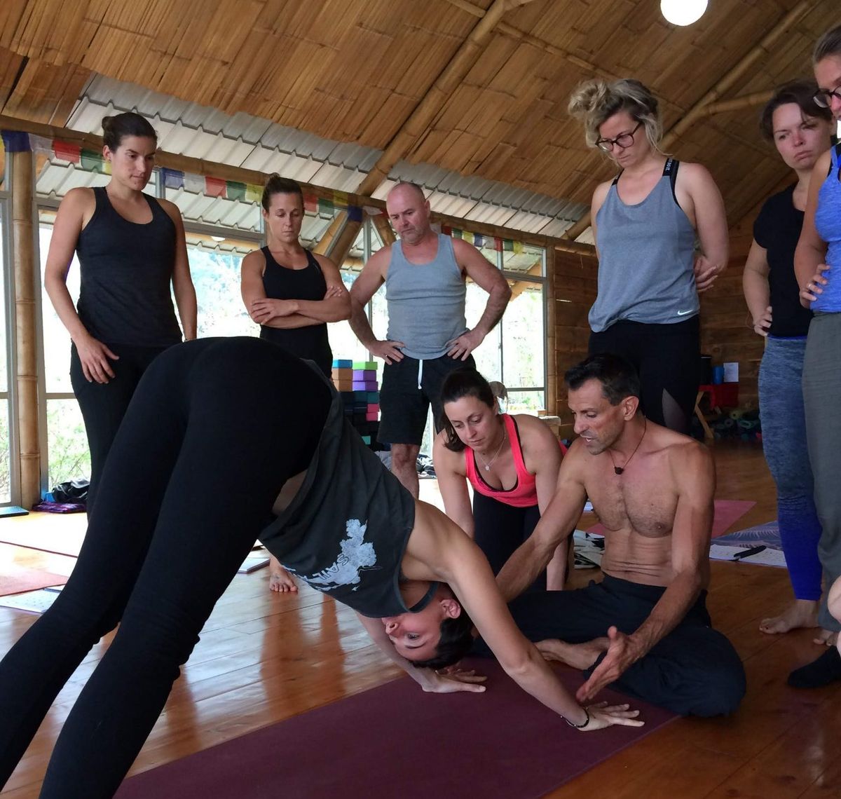 A morning yoga class standing in a wooden shala.