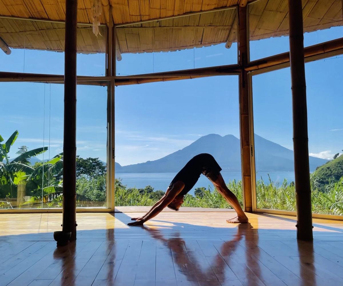 Downward-facing dog in a shala, with the lake and volcano behind.