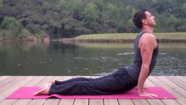 Cobra pose, chest lifted, by a lake.