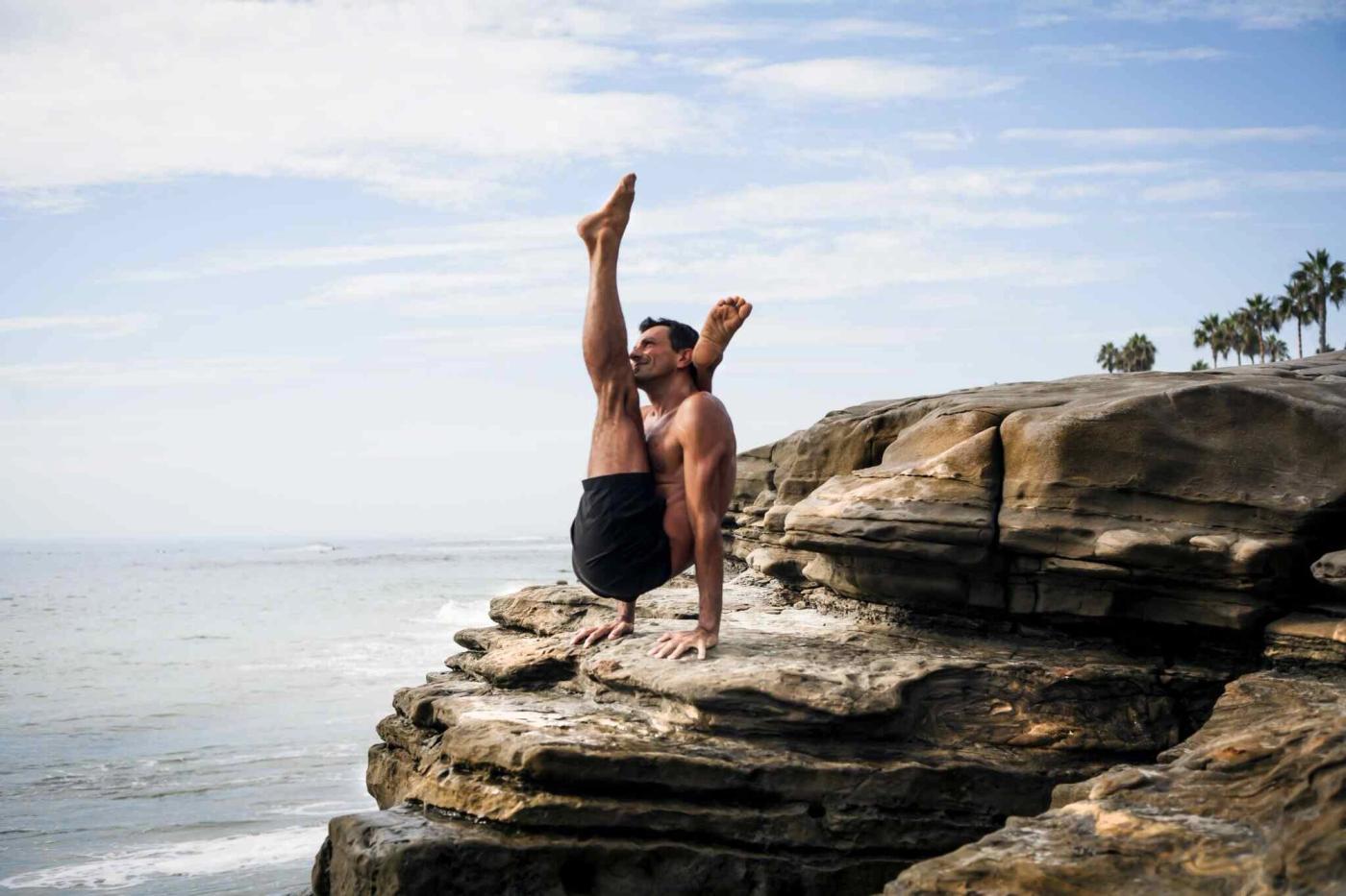 A forearm balance on the rocks, one leg lifted.