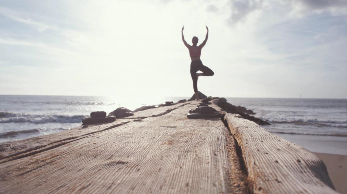 Tree pose on a pier over the ocean.
