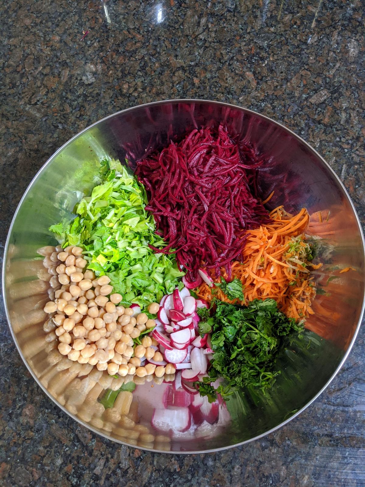 A bowl of chickpeas, avocado, beets, and greens.