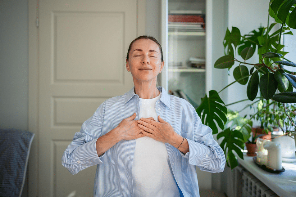 A woman with her eyes closed and both hands resting on her chest.