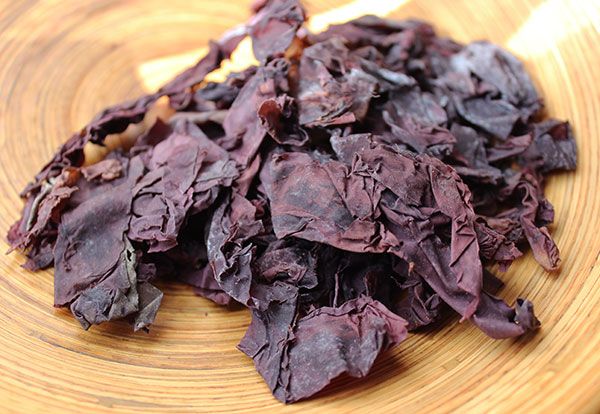 Dried purple dulse seaweed piled in a wooden bowl.