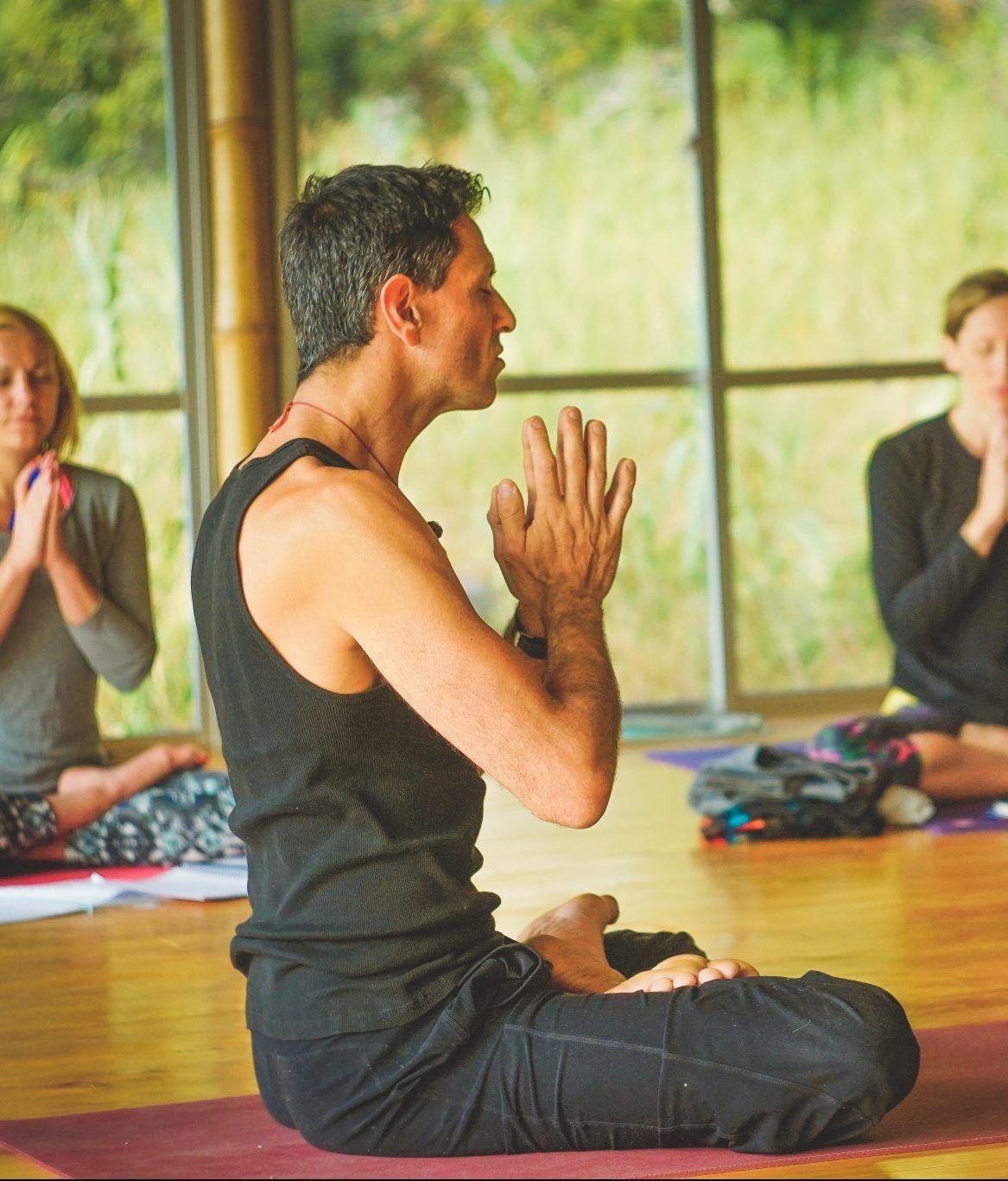 Seated in profile with eyes open and the gaze steady, hands together.