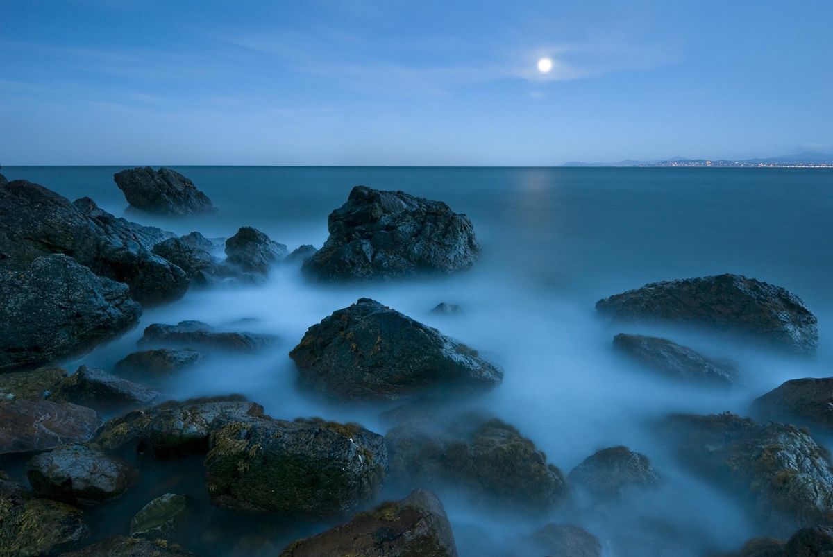 The moon over a calm sea at night.