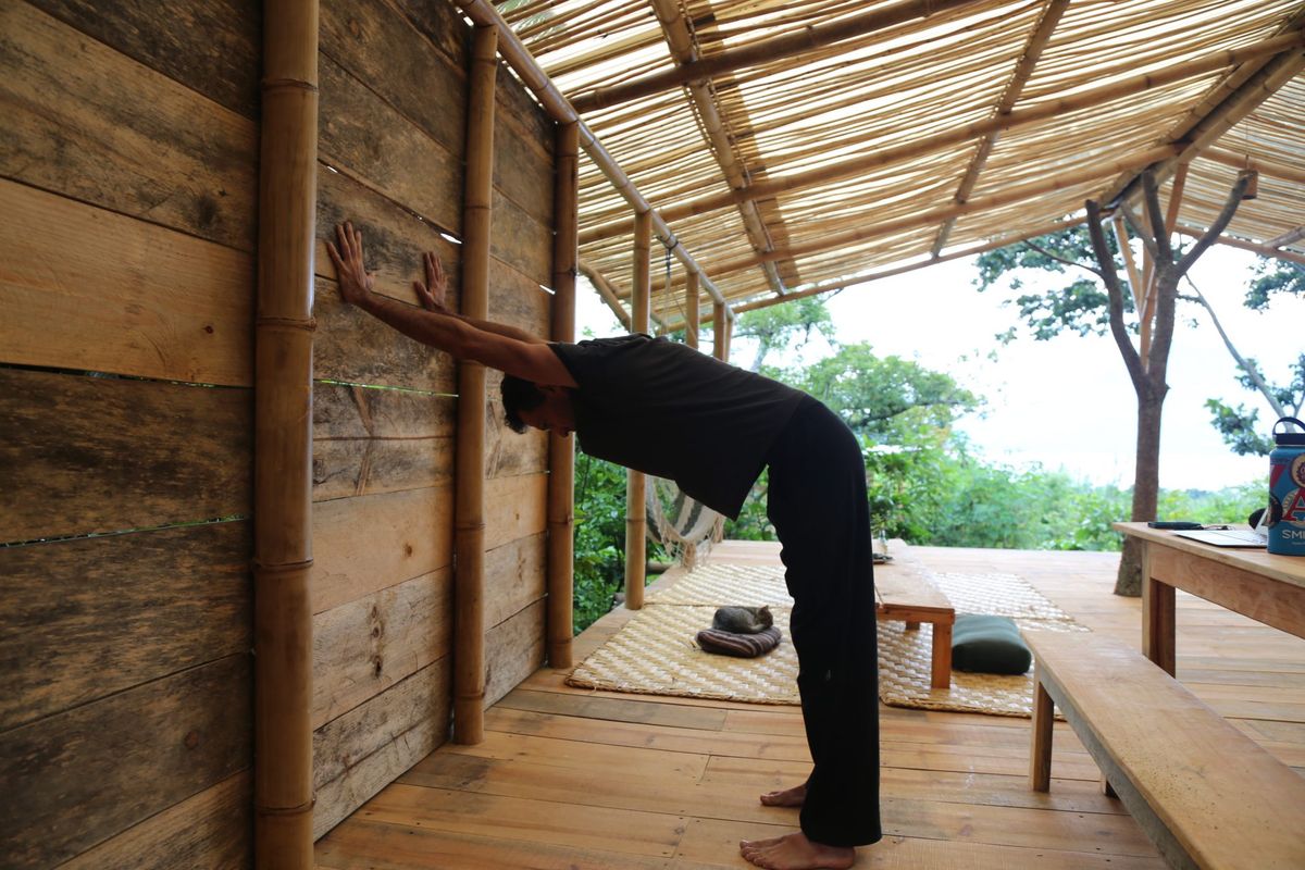 A standing forward fold with the hands on the wall.