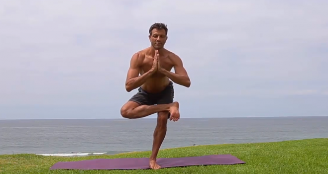 Tree pose, hands at the heart, standing on one leg.