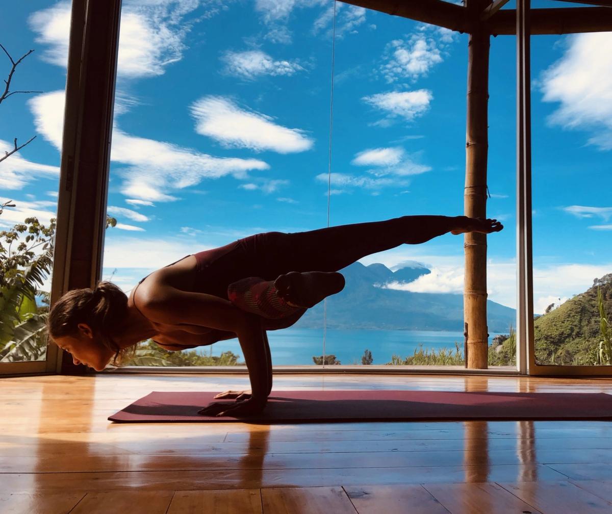 An arm balance in the shala, lake behind