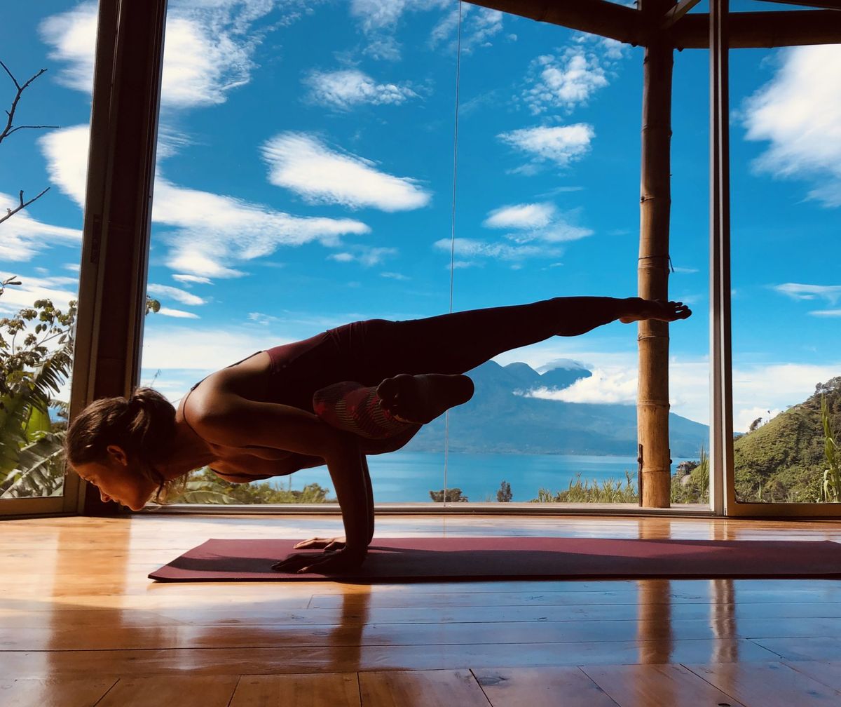 An arm balance in the shala, lake behind
