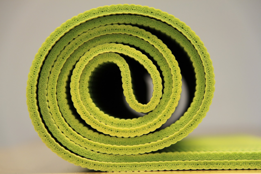 A green yoga mat rolled into a tight spiral.