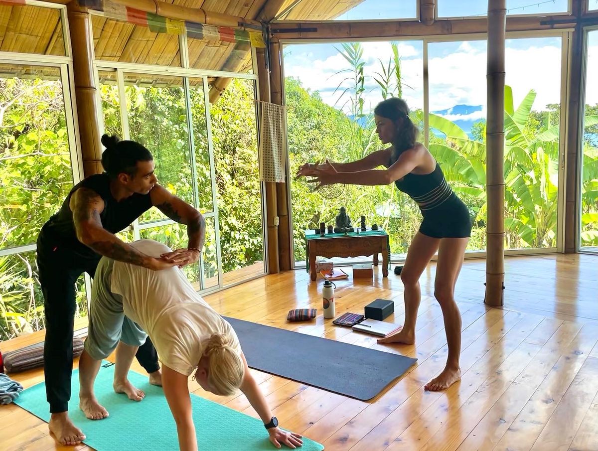 A hands-on assist at the hip in a standing pose.