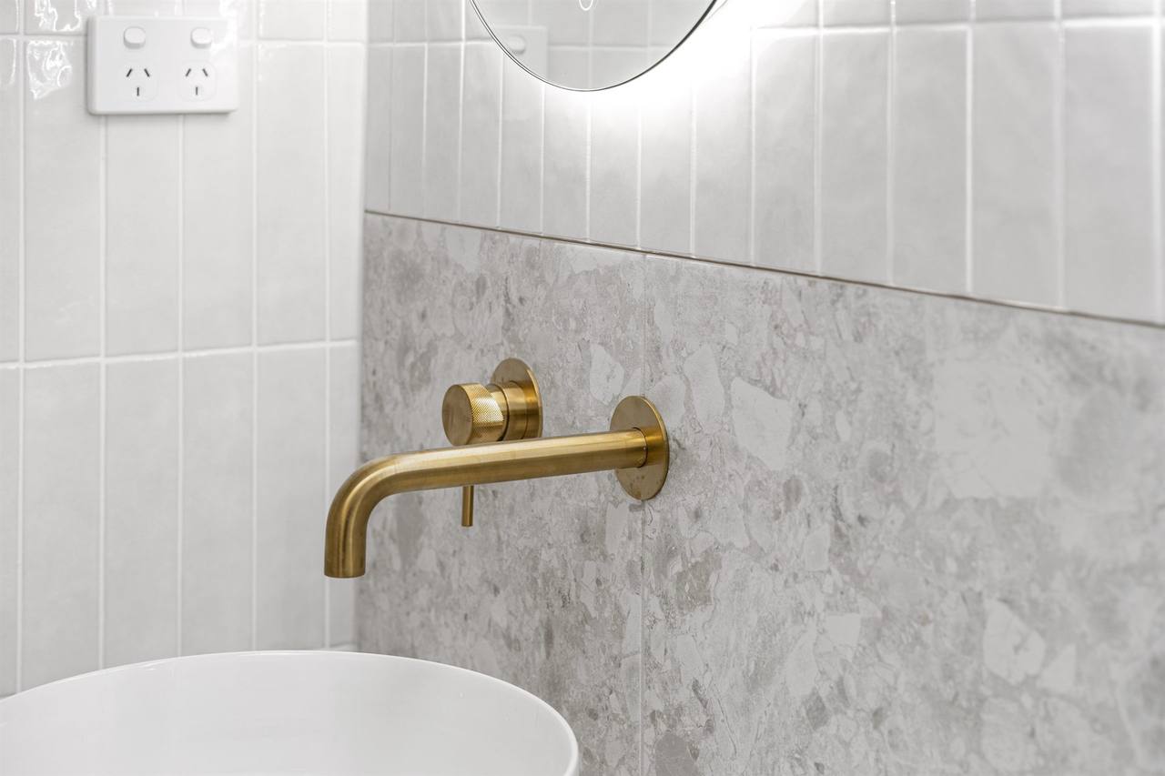 Brushed brass spout against grey terrazzo splashback macro detail