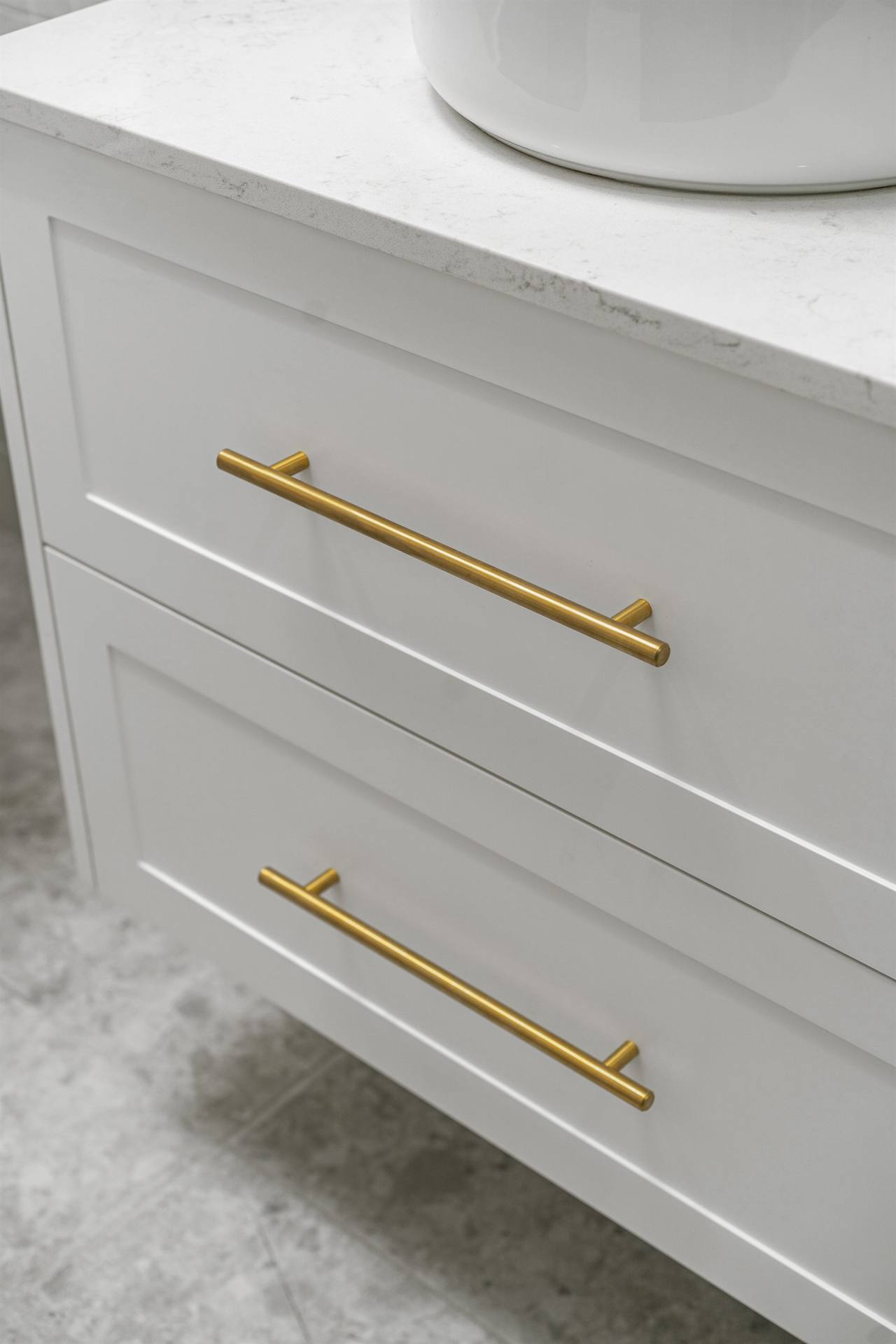 Brushed brass T-bar drawer pulls on custom white shaker vanity