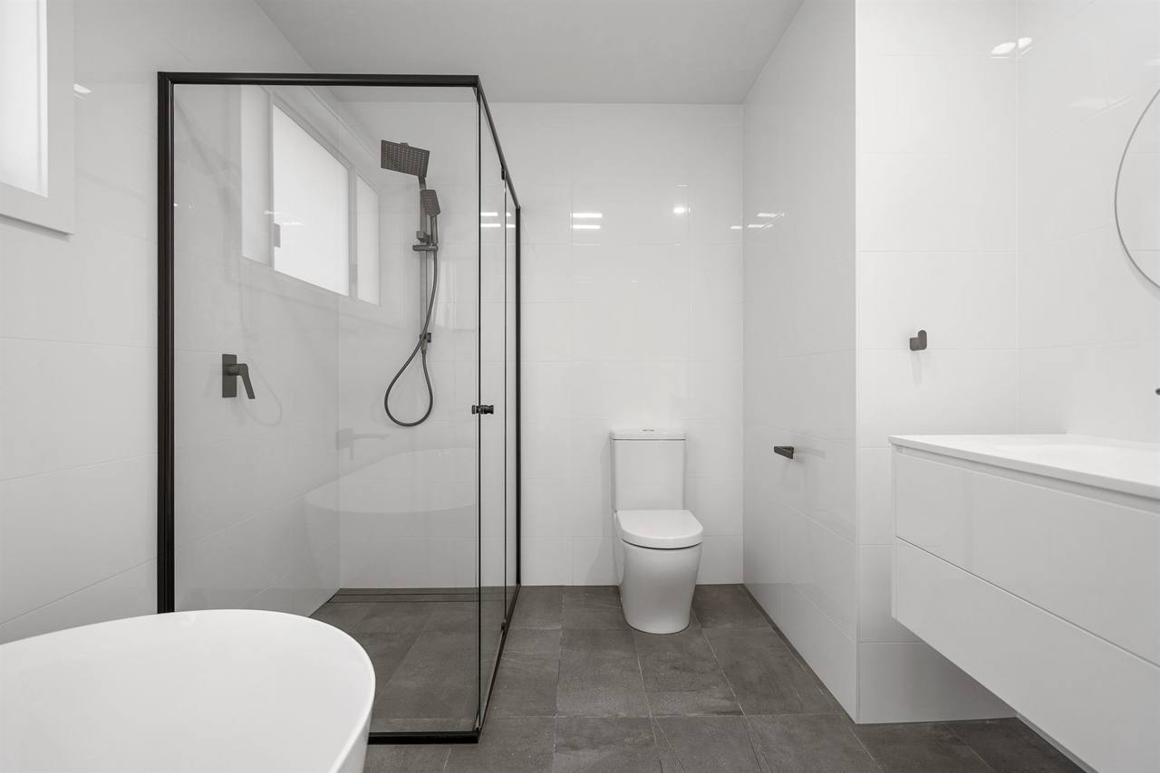Master bathroom with freestanding bath, black-framed shower screen and floating vanity