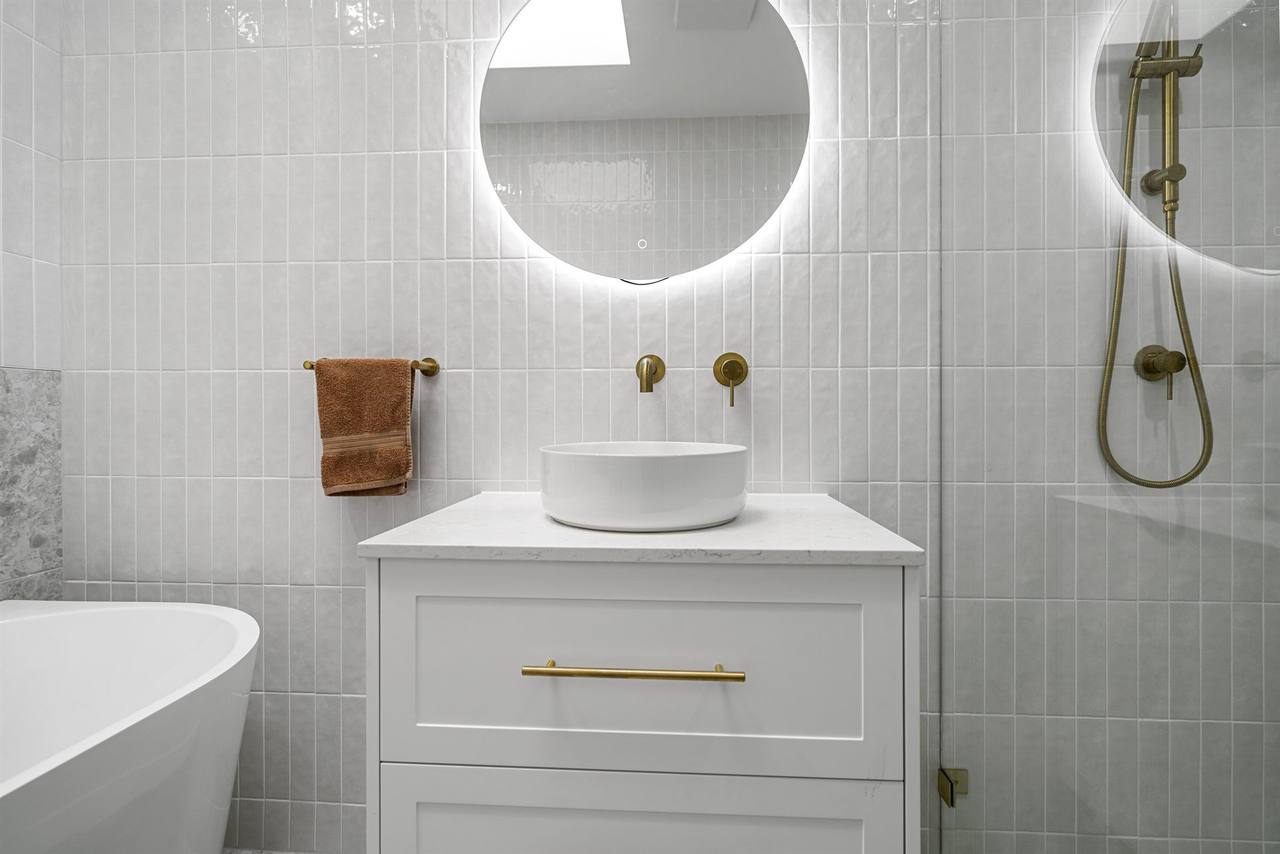 Wahroonga bathroom vanity with LED-lit oval mirror, brushed brass tapware and freestanding bath