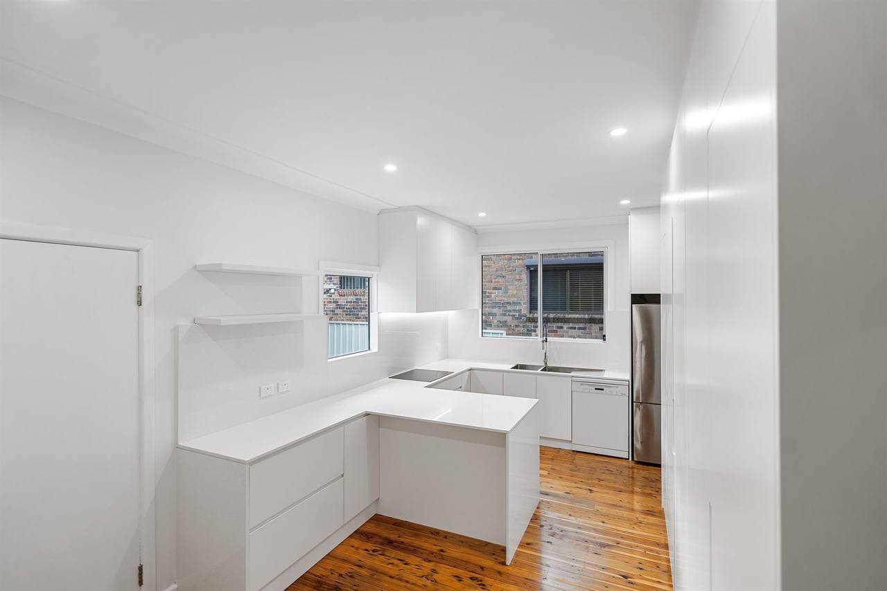 Wide angle of Berala compact kitchen showing U-shape and brick window view