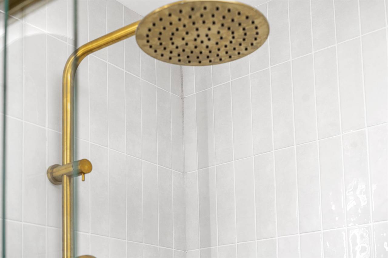 Brushed brass rainfall showerhead in vertical kit-kat tile shower
