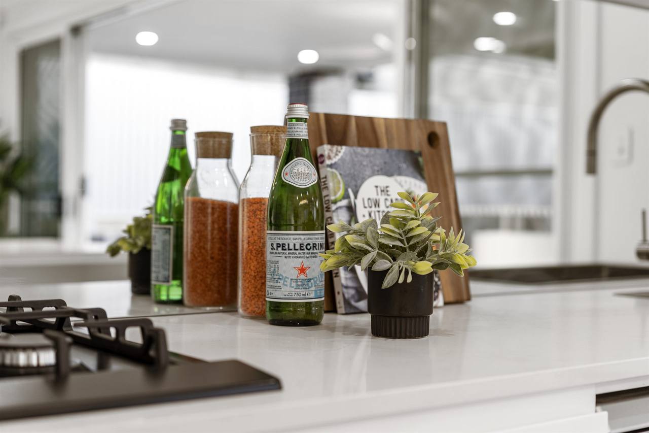 Kitchen counter detail — stone benchtop with timber chopping board and styled accents