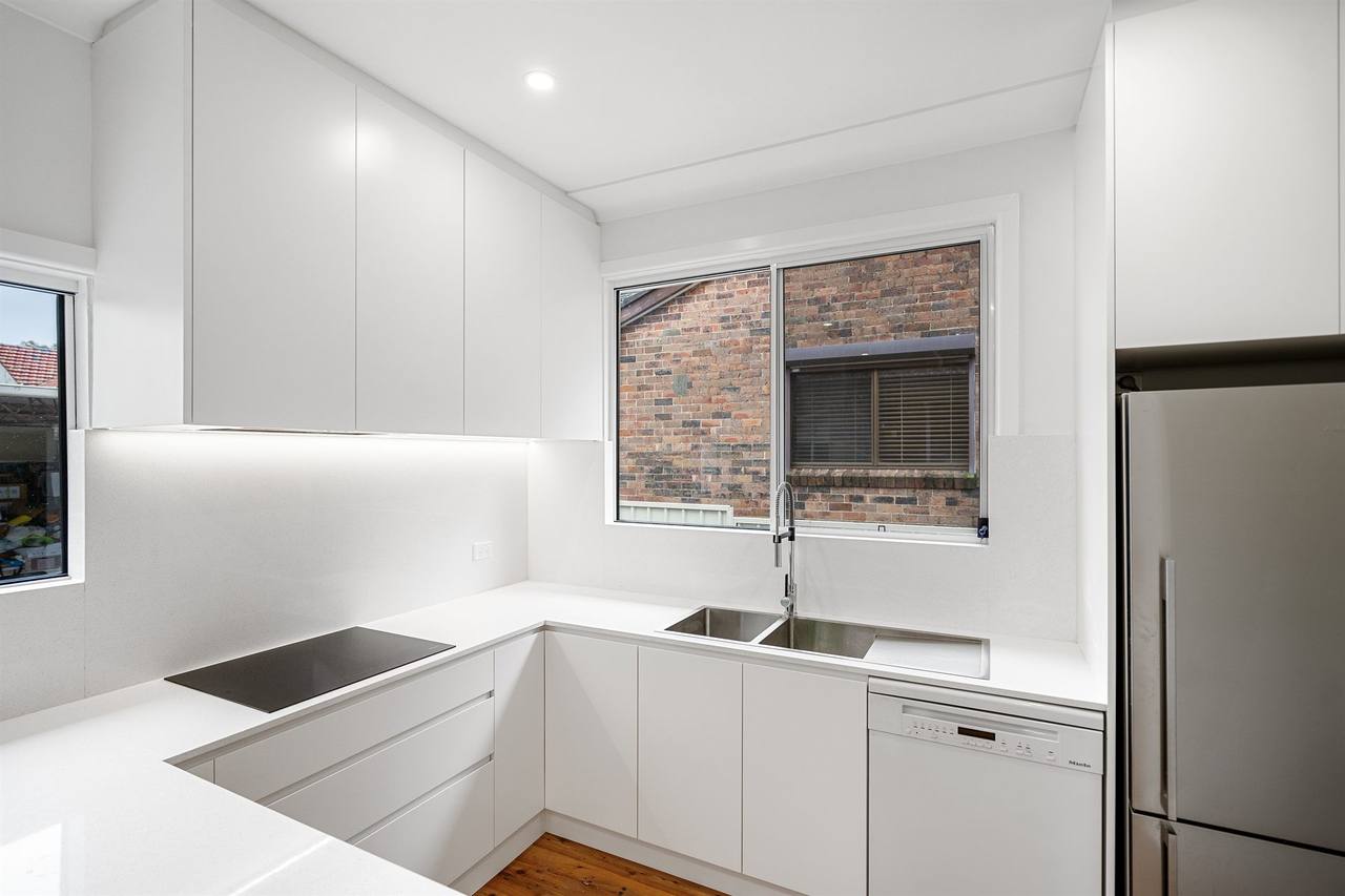 Berala kitchen cooktop area with brick view and white cabinetry