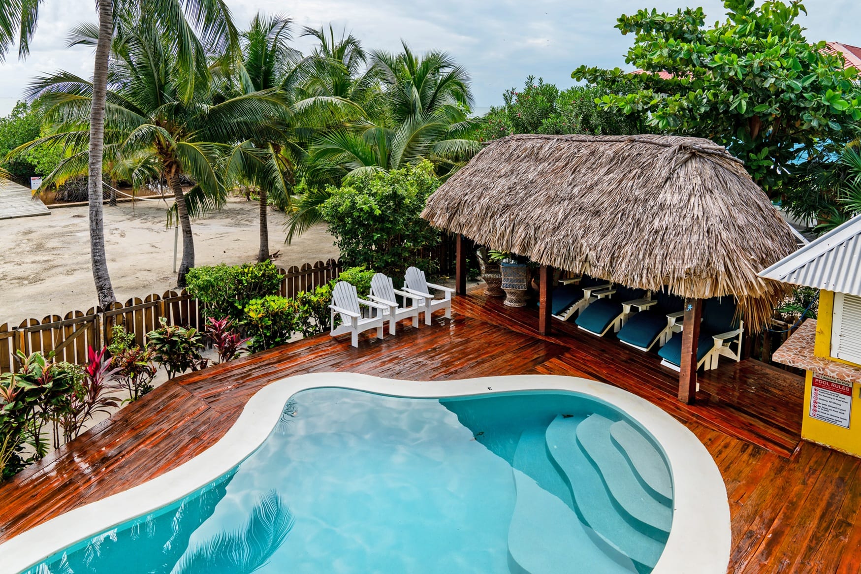 Aerial view of the pool deck with a thatched palapa and lounge chairs