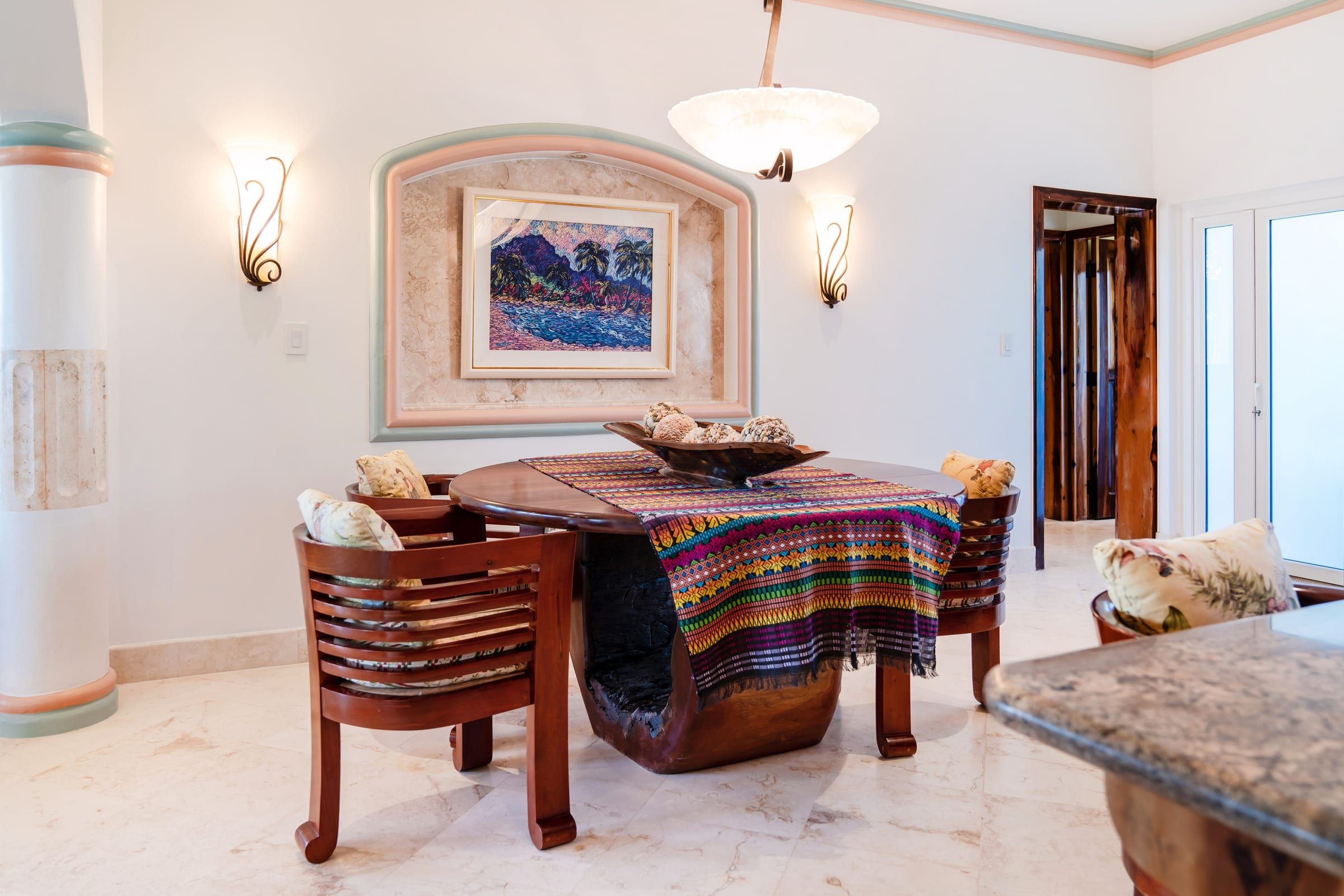 Round dining table with carved wood chairs and a framed painting