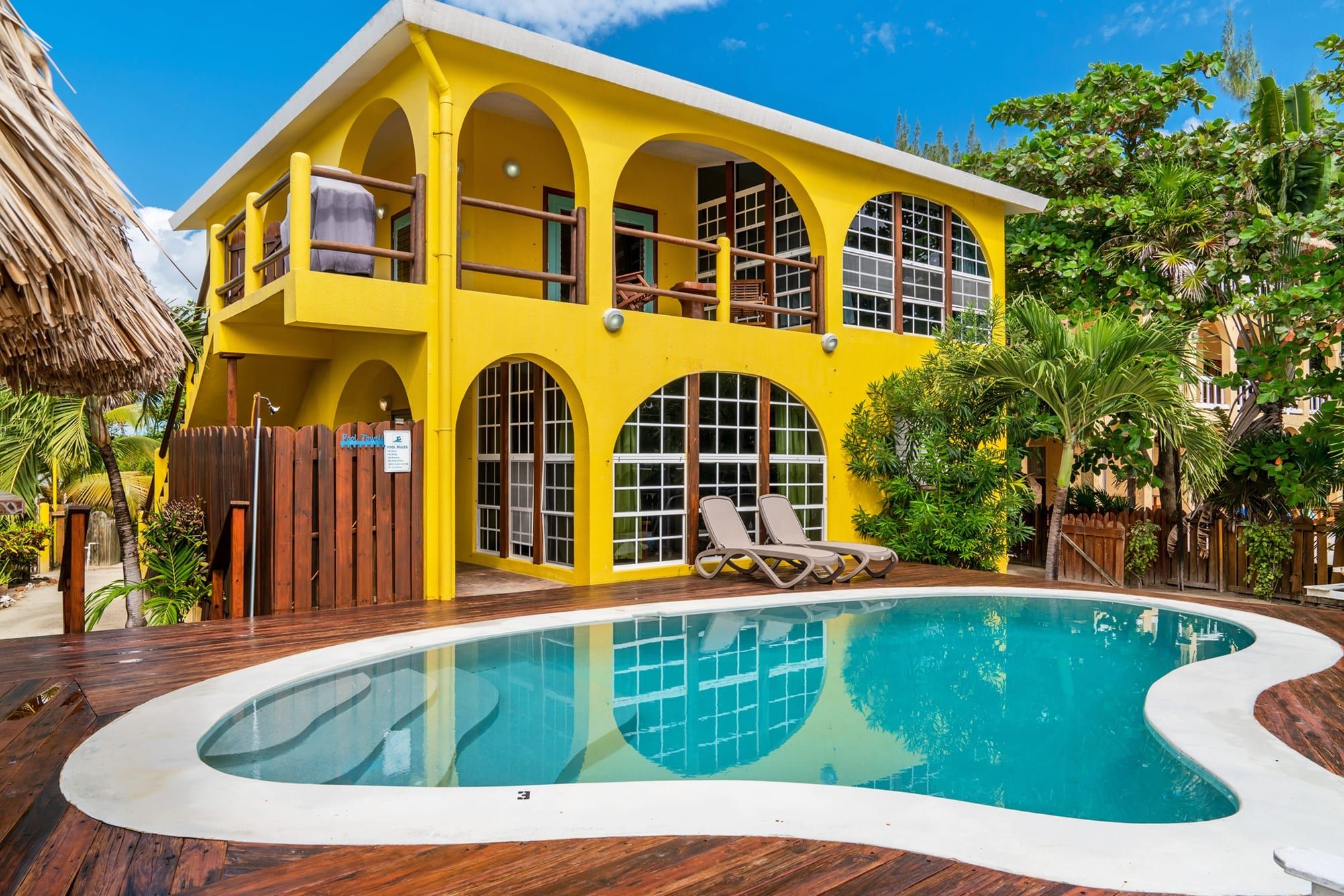 Yellow two-story oceanfront home with arched windows beside the swimming pool