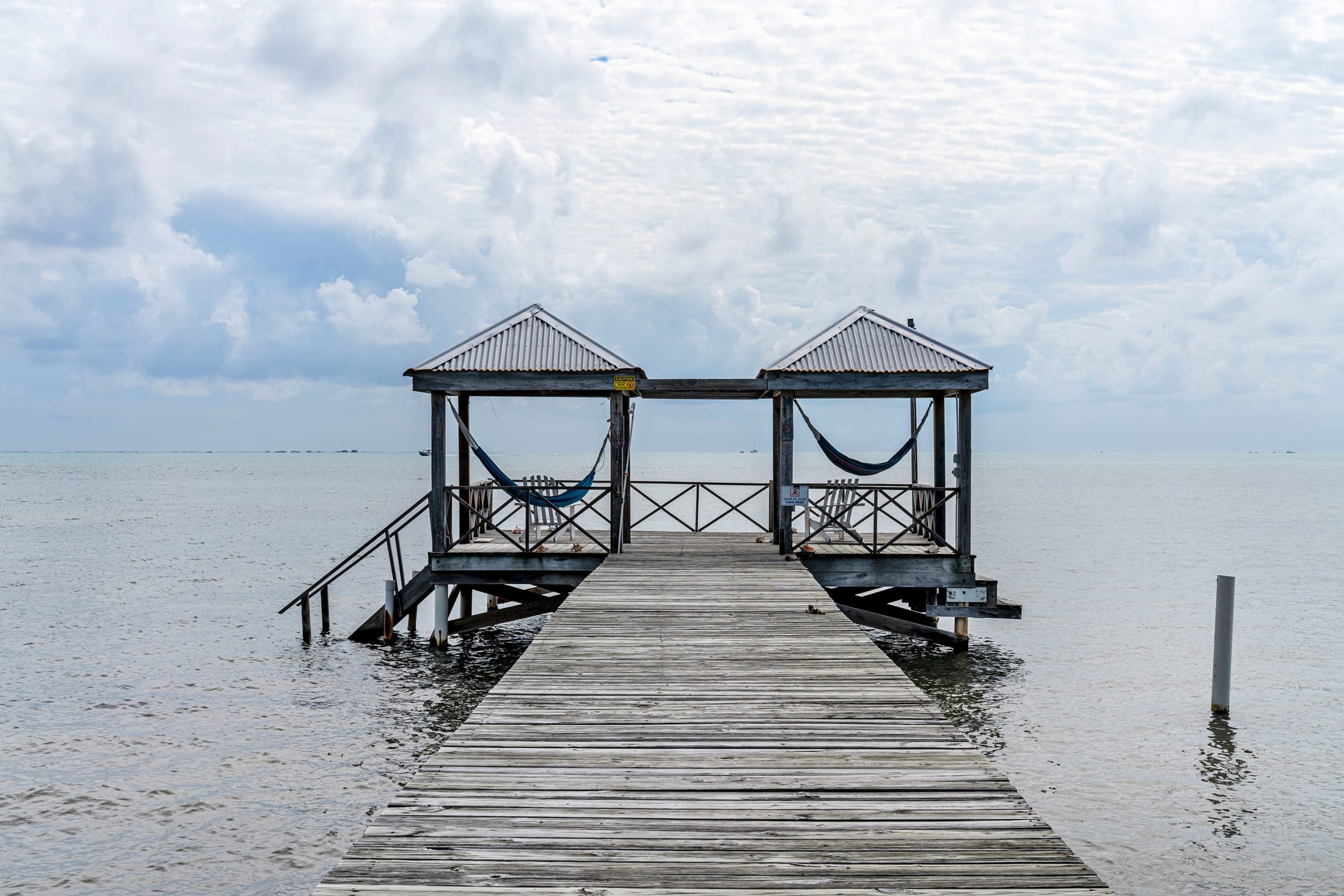 Long wooden pier with two covered palapas over the water