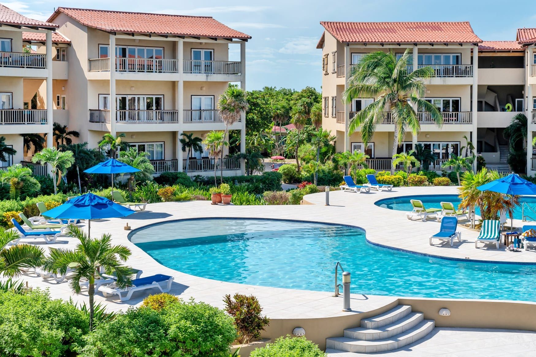 Resort pool and lounge chairs with terracotta-roofed buildings