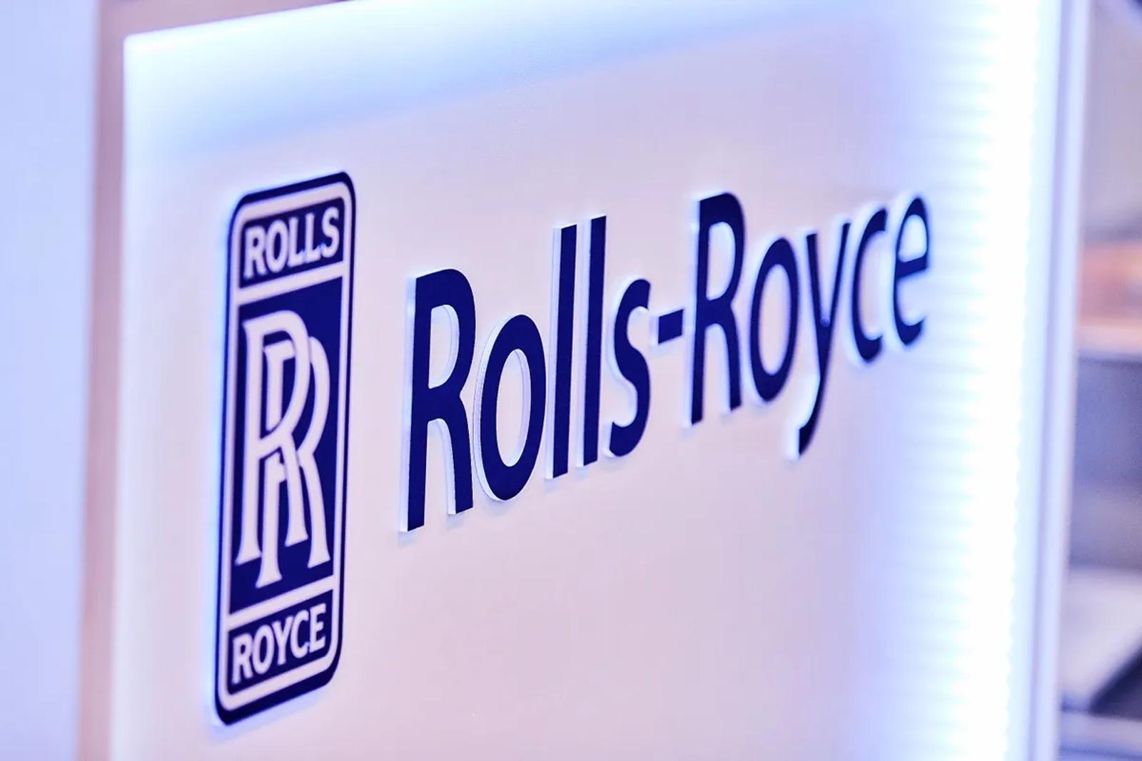 Backlit Rolls-Royce logo and name on a white exhibition stand wall