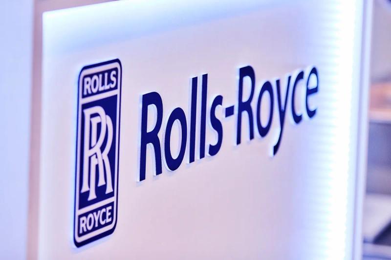 Backlit Rolls-Royce logo and name on a white exhibition stand wall