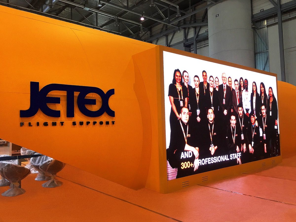 Large integrated LED screen running brand content on a custom exhibition stand built by Orchestra Media