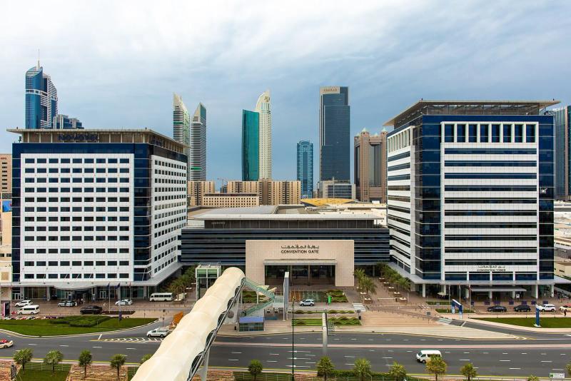 Convention Gate entrance building at Dubai World Trade Centre between two blue and white towers, with skyscrapers behind
