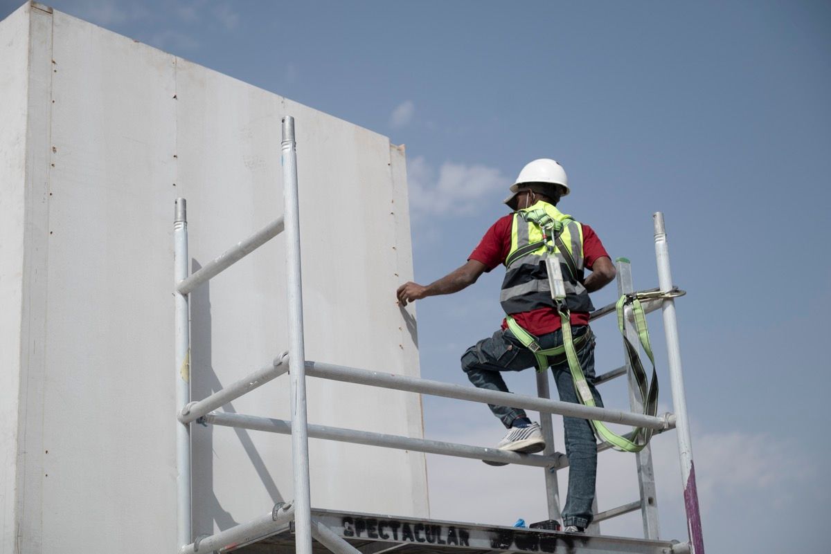 Stand construction crew member working at height during build-up at a defence exhibition