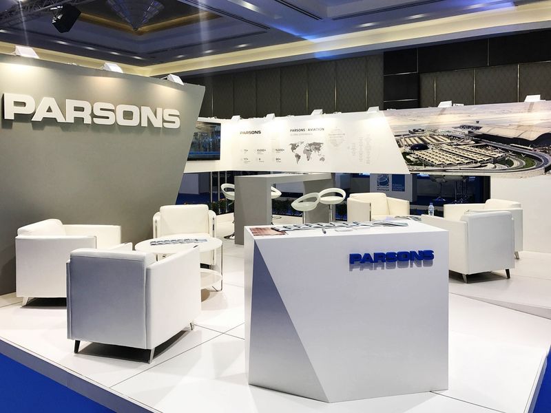 Bright corporate technology exhibition stand with meeting seating and a large branded wall, built by Orchestra Media