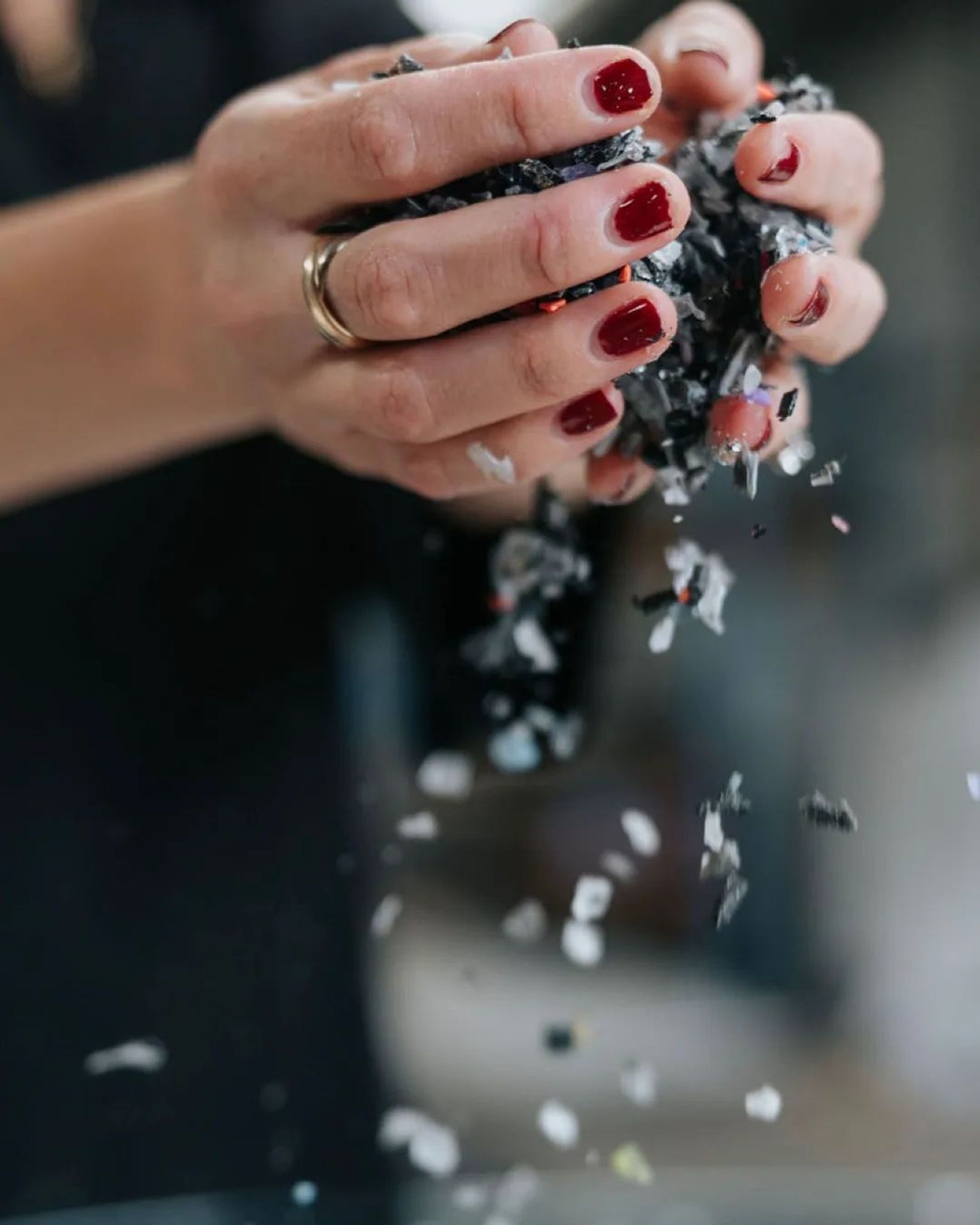Hands letting shredded phone case plastic fall through their fingers