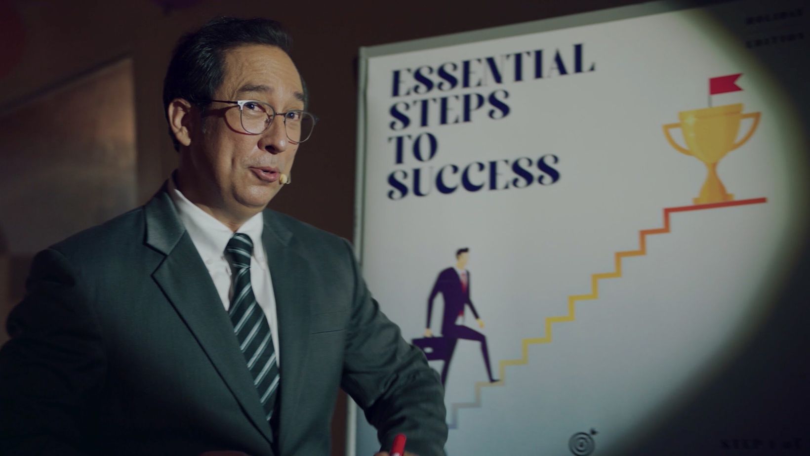 Film still of a motivational speaker presenting steps to success