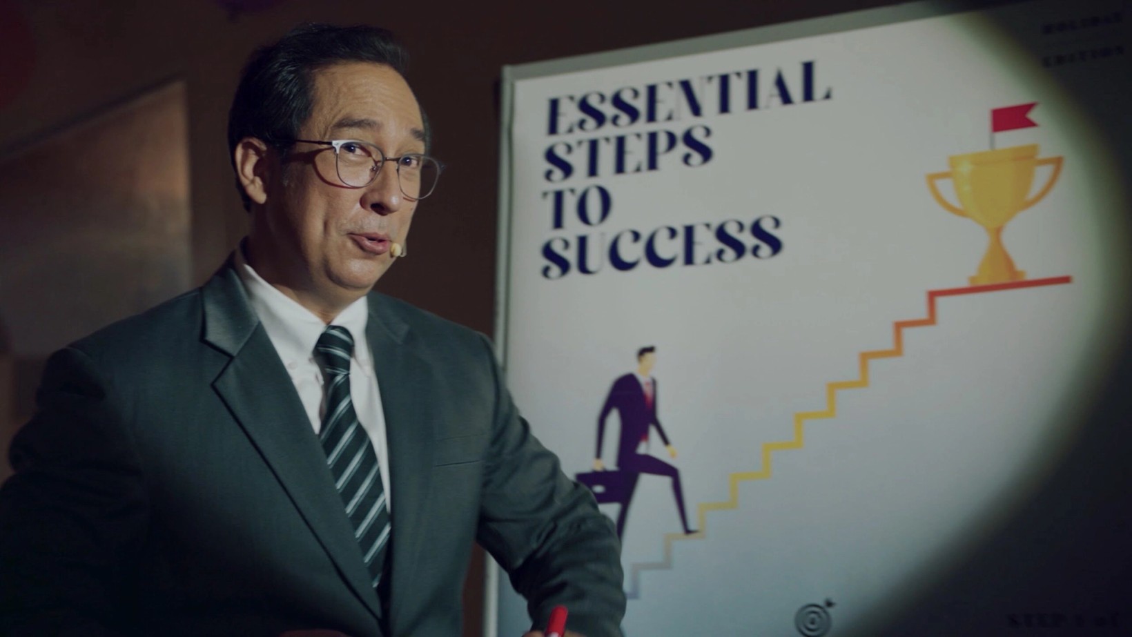 Film still of a motivational speaker presenting steps to success