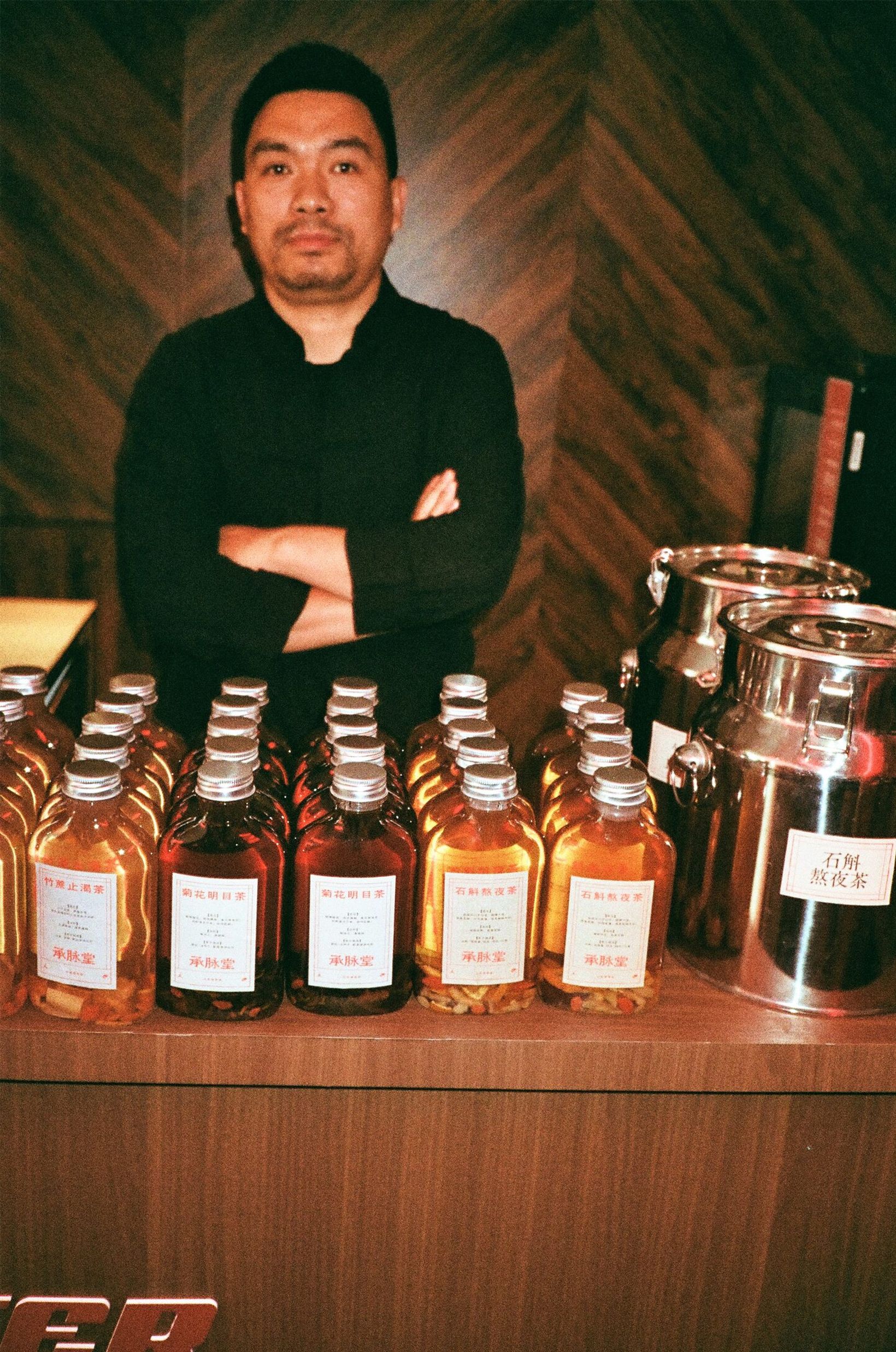 Herbalist behind the tea bar lined with bottled herbal blends
