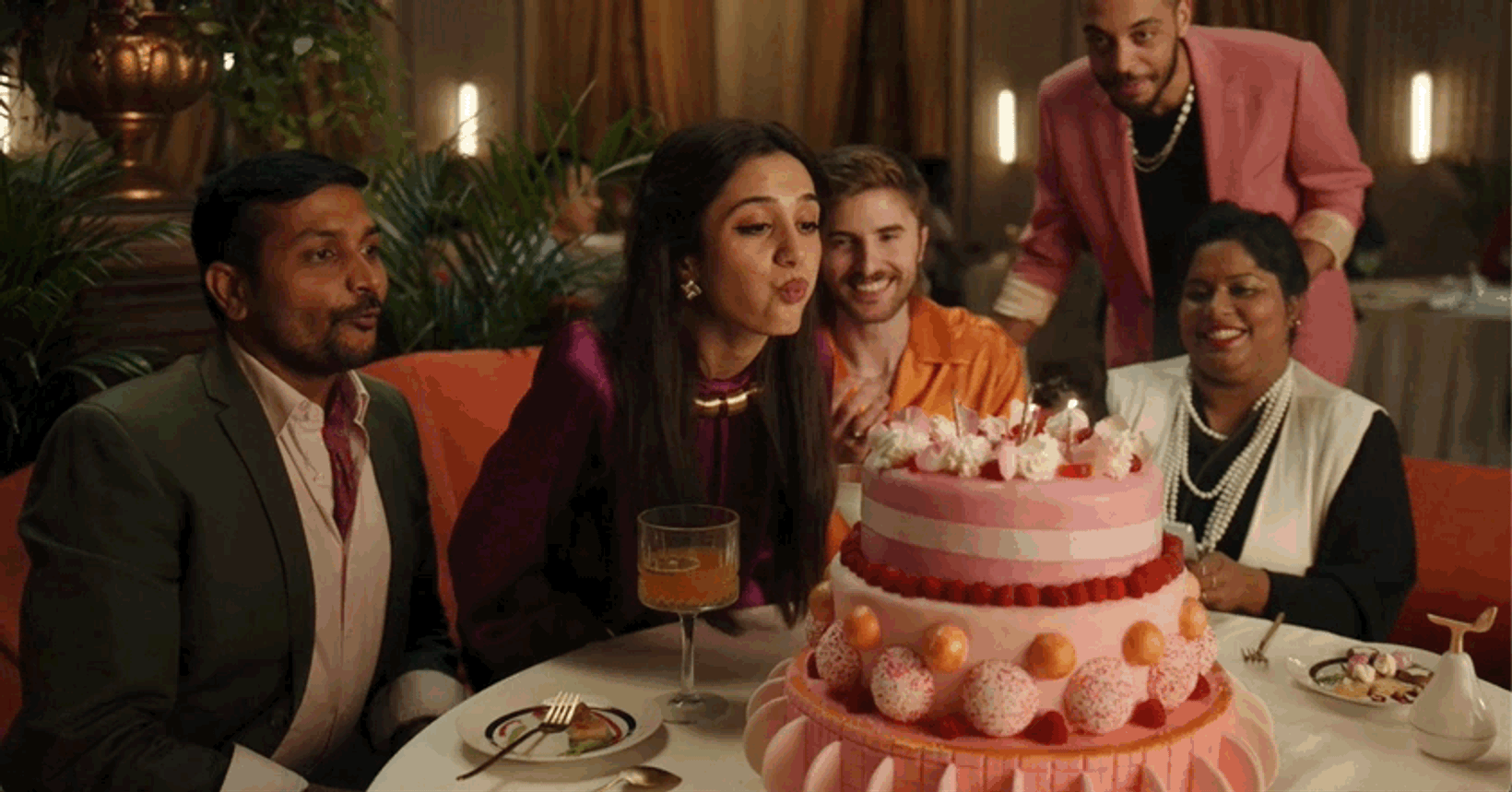 Guests gathered around a towering pink cake at a restaurant table