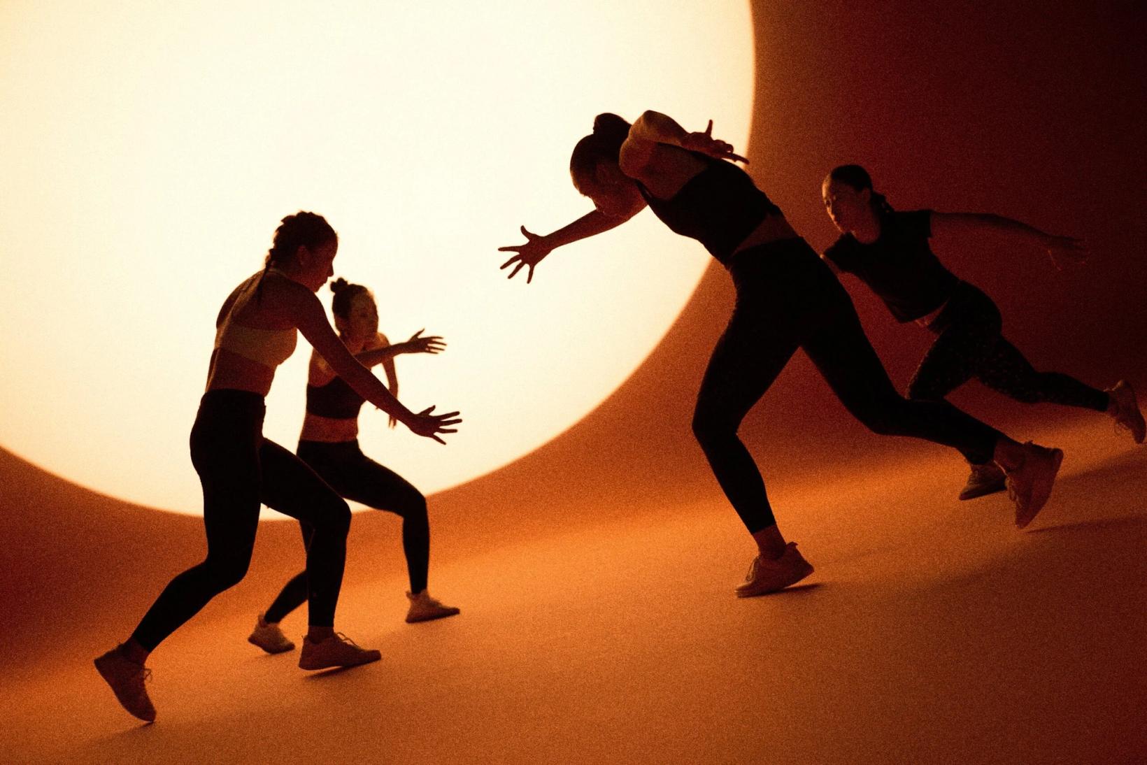 Silhouetted women sparring in front of a large glowing circle